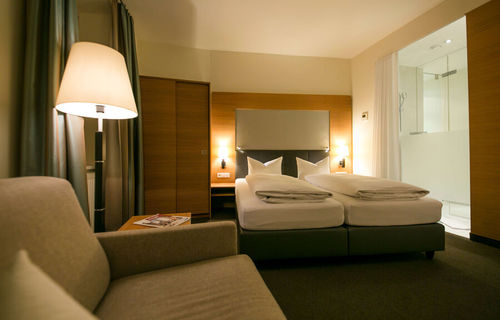 View into the business room of the Hotel Sailer with a double bed, a comfortable sofa and a floor lamp