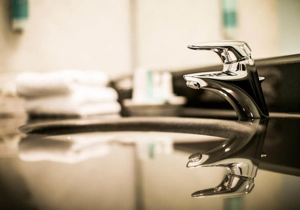 Eine silberne Armatur spiegelt sich auf den sauberen, schwarzen Waschbecken wieder.