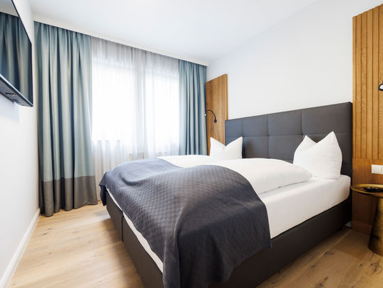 The modern double bed in the bedroom of the Deluxe Plus Apartment.