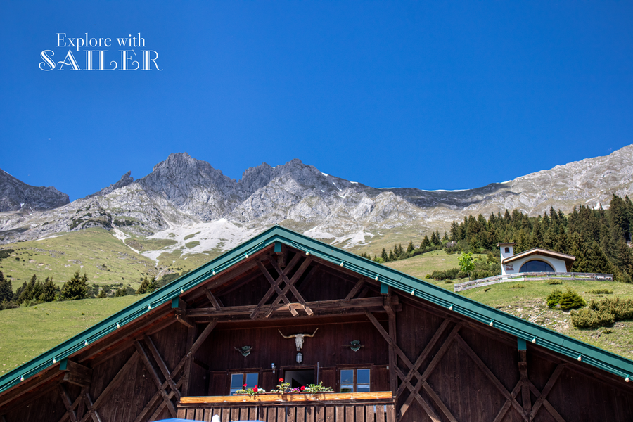 Dach der Höttinger Alm vor der Kulisse des Karwendelgebirges, daneben die kleine Kapelle bei der Höttinger Alm.