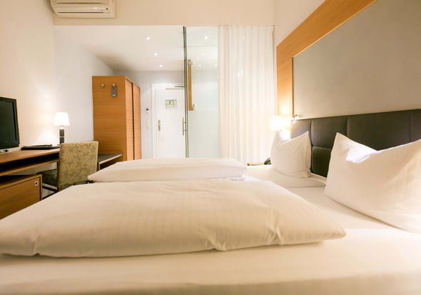 Zwei Kissen und zwei Bettdecken liegen auf einem Doppelbett im Businesszimmer