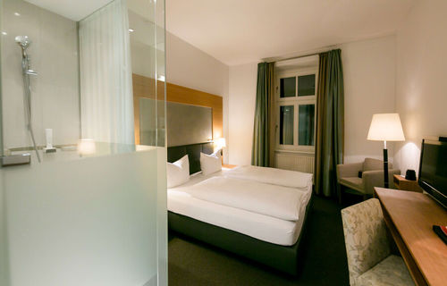 View into the business room of Hotel Sailer with a double bed, a comfortable sofa and a floor lamp
