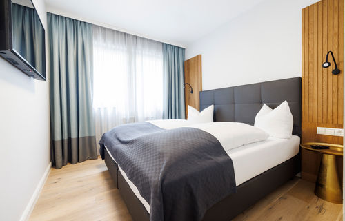 The modern double bed in the bedroom of the Deluxe Plus Apartment.