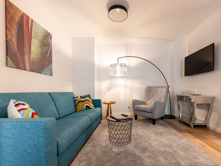 Il moderno soggiorno dell'appartamento Delux XL con divano, tappeto, tavolo e molto altro.