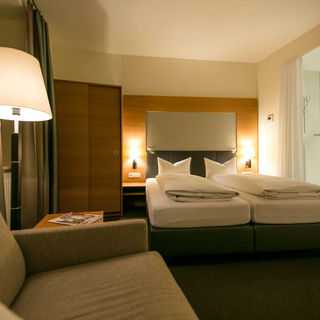 View into the business room of the Hotel Sailer with a double bed, a comfortable sofa and a floor lamp