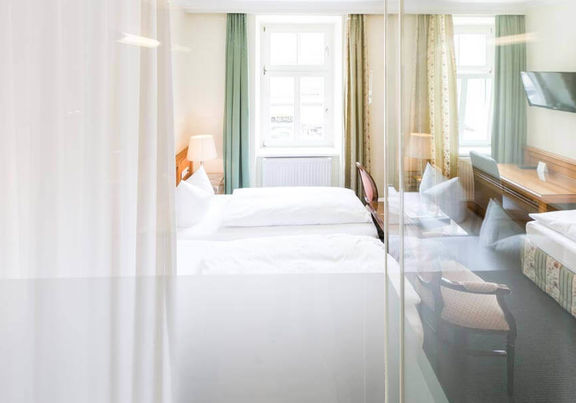 Blick in das Dreibettzimmer mit einem Doppelbett und einem Einzelbett, sowie einem Schreibtisch und einem Fernseher