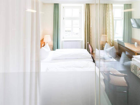 Blick in das Dreibettzimmer mit einem Doppelbett und einem Einzelbett, sowie einem Schreibtisch und einem Fernseher