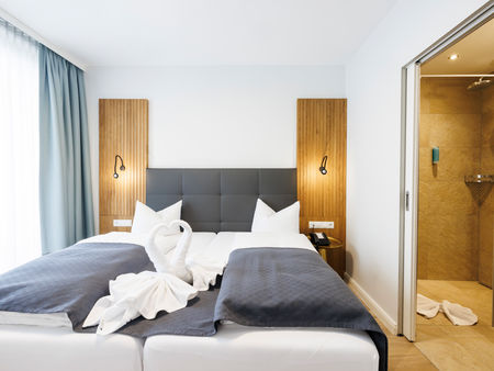 Das Doppelbett im Apartment Komfort Plus worauf aus Handtüchern zwei Schwäne die ein Herz zeigen gefaltet sind.