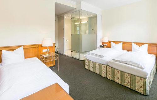 View into the triple room with a double bed and a single bed, as well as a desk and a TV set.