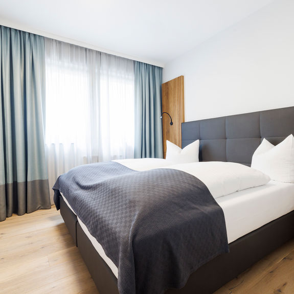 The modern double bed in the bedroom of the Deluxe Plus Apartment.