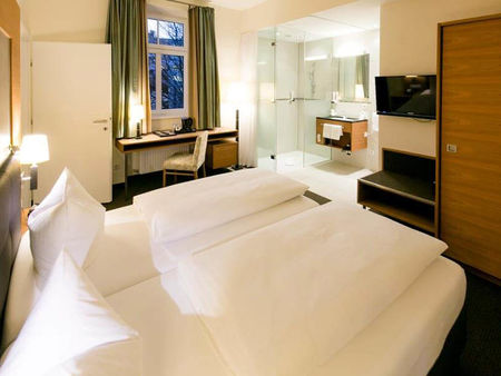 Un comodo letto si trova al centro di una suite. La stanza ha un bagno con porte di vetro e una porta per la seconda stanza.