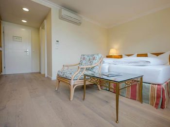 Ein Blumenstuhl mit dazugehörigen Glastisch steht vor dem Doppelbett.