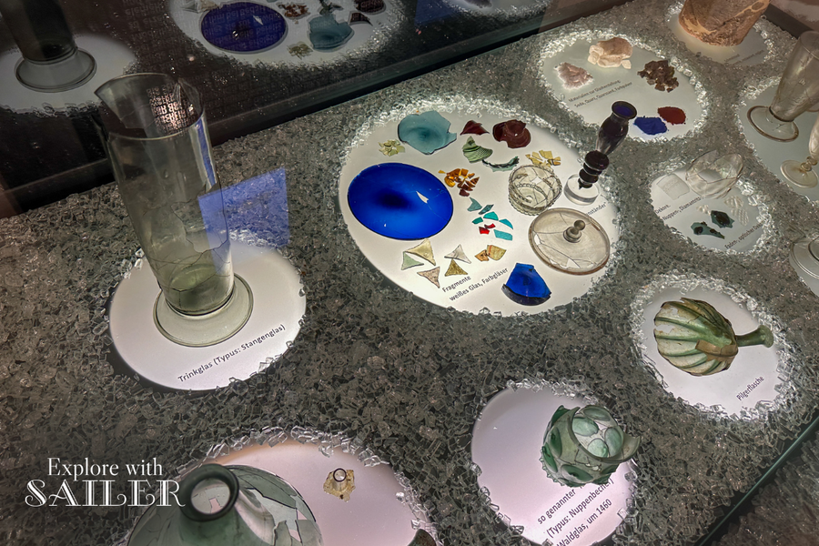 Exhibition featuring historic glassware, glass fragments, and various glassmaking techniques at the Hall Mint.