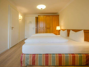 Ein bezogenes Doppelbett steht in der Mitte des Hotelzimmers, daneben ist ein großer Kleiderschrank