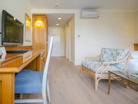 Das Klassik Zimmer im Hotel Sailer mit einem Schreibtisch, einem Holzboden und einer Bank im Blumenmuster