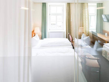 Blick in das Dreibettzimmer mit einem Doppelbett und einem Einzelbett, sowie einem Schreibtisch und einem Fernseher