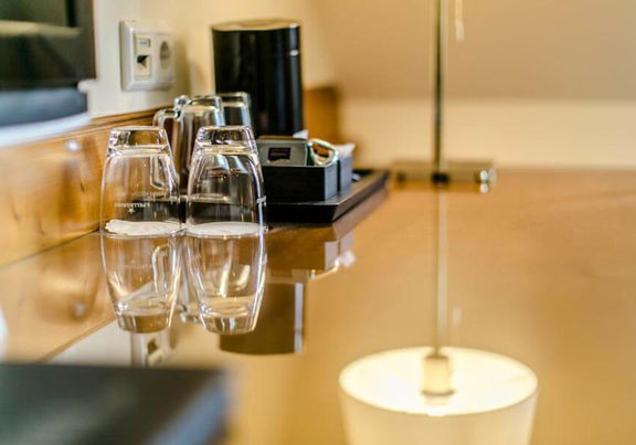 Ein paar Gläser stehen auf einen Schreibtisch mit Glasplatte.