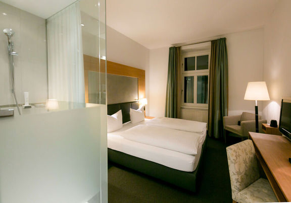 Blick in das Businesszimmer des Hotel Sailer mit einem Doppelbett, einem gemütlichen Sofa und einer Stehlampe