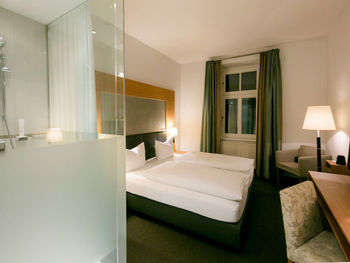 Blick in das Businesszimmer des Hotel Sailer mit einem Doppelbett, einem gemütlichen Sofa und einer Stehlampe