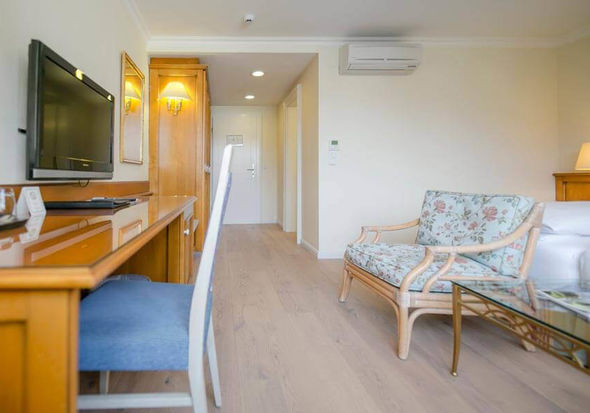 Das Klassik Zimmer im Hotel Sailer mit einem Schreibtisch, einem Holzboden und einer Bank im Blumenmuster