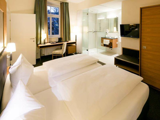 Un comodo letto si trova al centro di una suite. La stanza ha un bagno con porte di vetro e una porta per la seconda stanza.