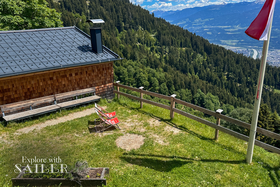 Liegestühle neben der Höttinger Alm mit Blick über den Wald, das Inntal und die Stadt Innsbruck.