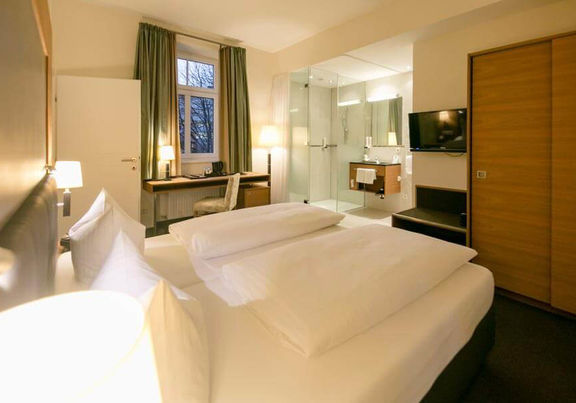 Un comodo letto si trova al centro di una suite. La stanza ha un bagno con porte di vetro e una porta per la seconda stanza.