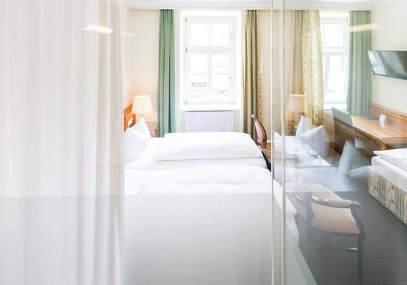 Blick in das Dreibettzimmer mit einem Doppelbett und einem Einzelbett, sowie einem Schreibtisch und einem Fernseher