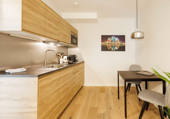 Die kleine Küche im Apartment mit Tisch und Stühlen.