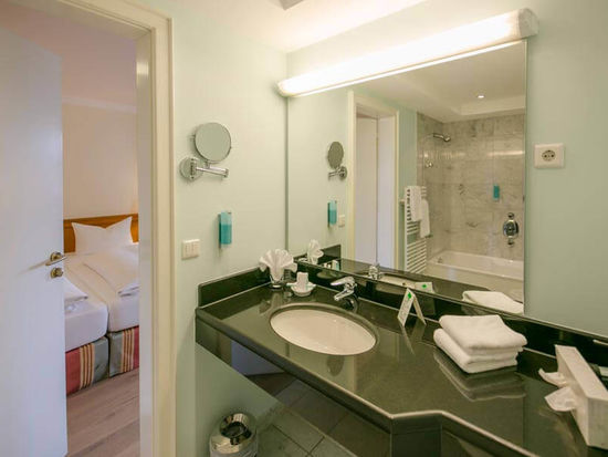 Il bagno ha un grande specchio e un lavabo nero lucido.