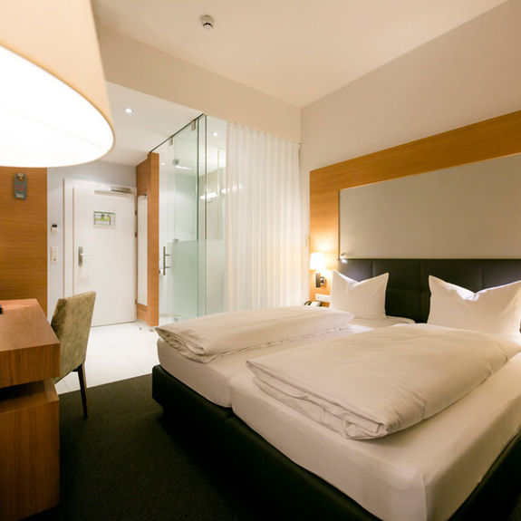 View into the business room of Hotel Sailer with a double bed, a comfortable sofa and a floor lamp