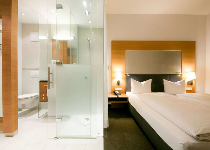 View into the business room of the Hotel Sailer with a double bed and a large bathroom with shower