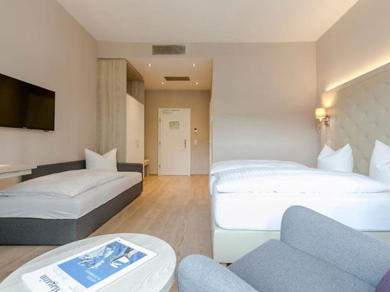 Ein Doppelbett und ein Einzelbett mit einer hellen erleuchteten Hotelzimmer