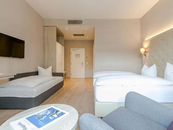 Ein Doppelbett und ein Einzelbett mit einer hellen erleuchteten Hotelzimmer