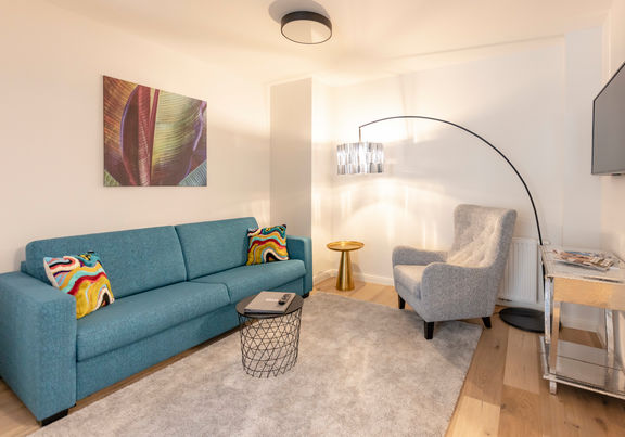 Il moderno soggiorno dell'appartamento Delux XL con divano, tappeto, tavolo e molto altro.