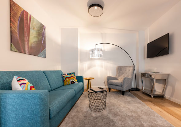 Il moderno soggiorno dell'appartamento Delux XL con divano, tappeto, tavolo e molto altro.