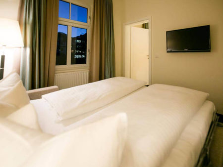 Bettwäsche liegt auf einem ausziehbaren Sofa und ein Flachbildschirm-Fernseher hängt an der Wand