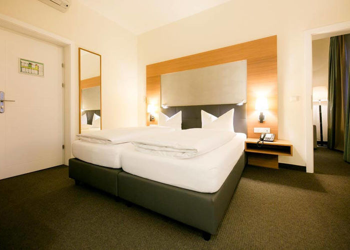 Ein großes Doppelbett steht in einem großen Zimmer mit einem Teppichboden