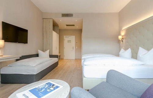 Ein Doppelbett und ein Einzelbett mit einer hellen erleuchteten Hotelzimmer