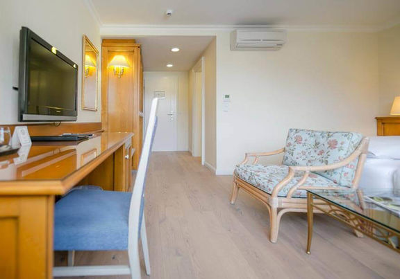 Das Klassik Zimmer im Hotel Sailer mit einem Schreibtisch, einem Holzboden und einer Bank im Blumenmuster