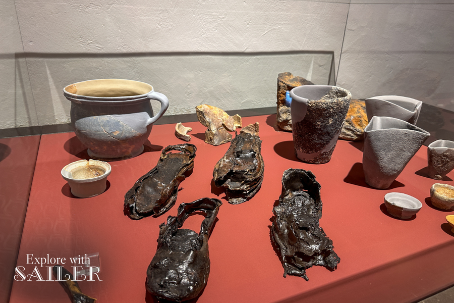 Historische Keramikgefäße, Schuhe und weitere archäologische Fundstücke in einer Ausstellung der Münze Hall.