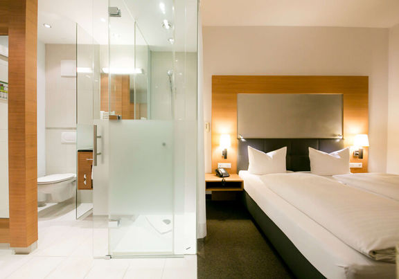 Blick in das Businesszimmer des Hotel Sailer mit einem Doppelbett und einem großen Badezimmer mit Dusche