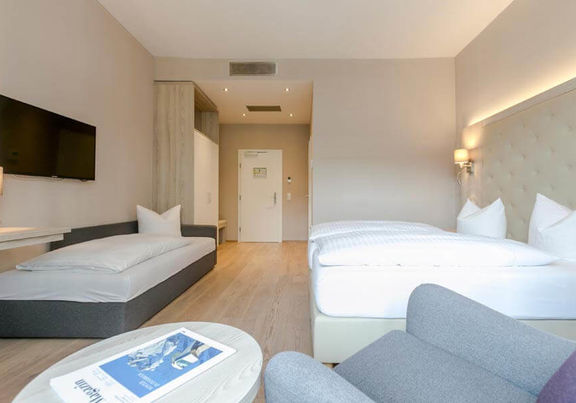 Ein Doppelbett und ein Einzelbett mit einer hellen erleuchteten Hotelzimmer