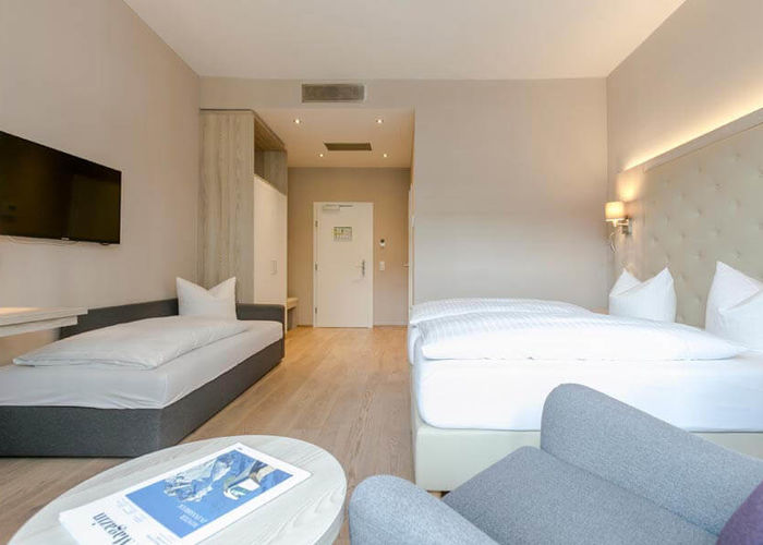 Ein Doppelbett und ein Einzelbett mit einer hellen erleuchteten Hotelzimmer