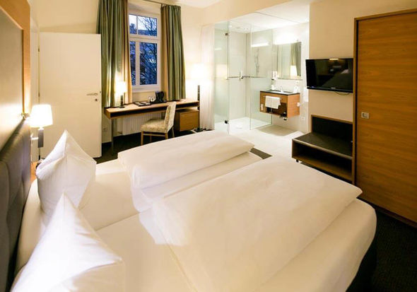 Un comodo letto si trova al centro di una suite. La stanza ha un bagno con porte di vetro e una porta per la seconda stanza.