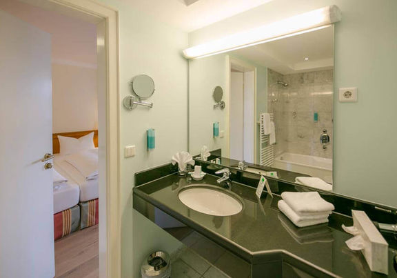 Il bagno ha un grande specchio e un lavabo nero lucido.