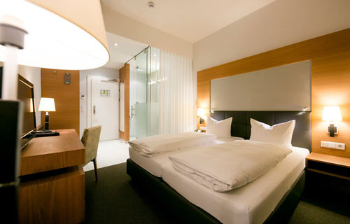 View into the business room of Hotel Sailer with a double bed, a comfortable sofa and a floor lamp