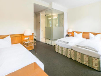 Blick in das Dreibettzimmer mit einem Doppelbett und einem Einzelbett, sowie einem Schreibtisch und einem Fernseher