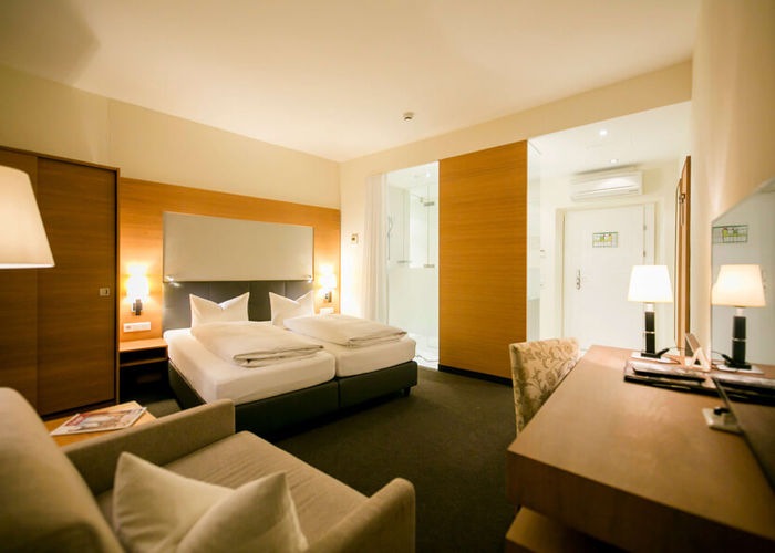 View into the business room of the Hotel Sailer with a double bed, a comfortable sofa and a floor lamp