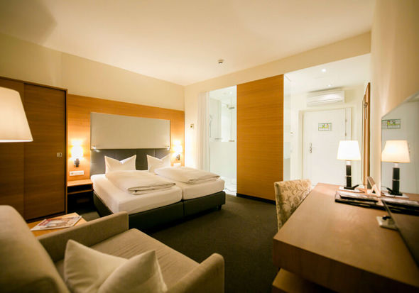 View into the business room of the Hotel Sailer with a double bed, a comfortable sofa and a floor lamp